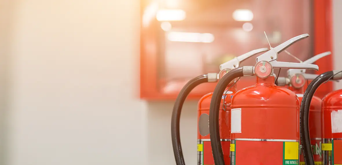 Red fire extinguishers next to a wall fire panel